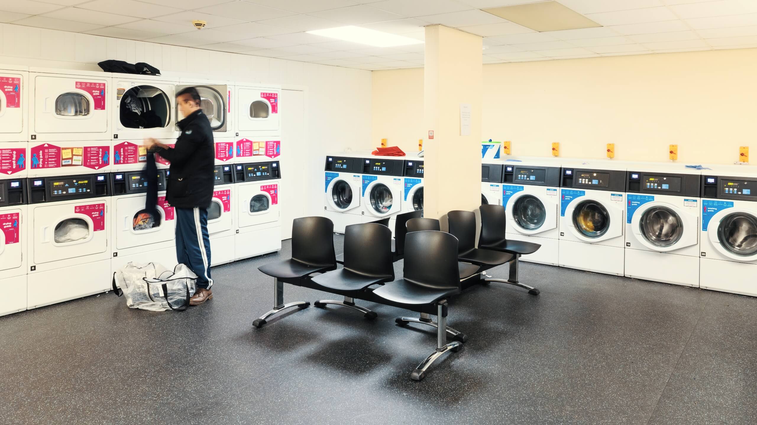 A student loads washing into a tumble dryer in one of the laundrettes.