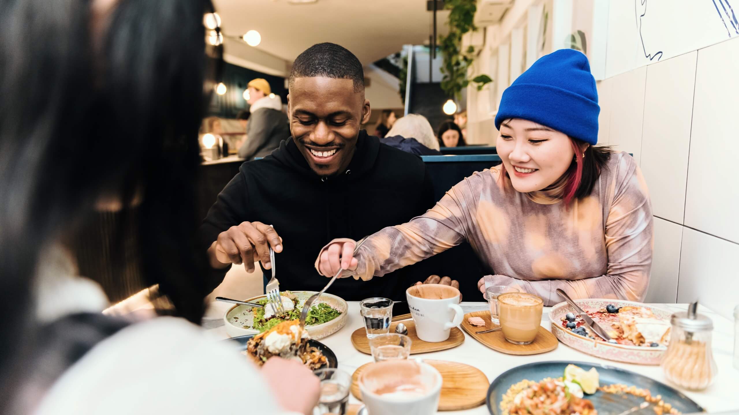 Two smiling students tuck into a meal in a restaurant.