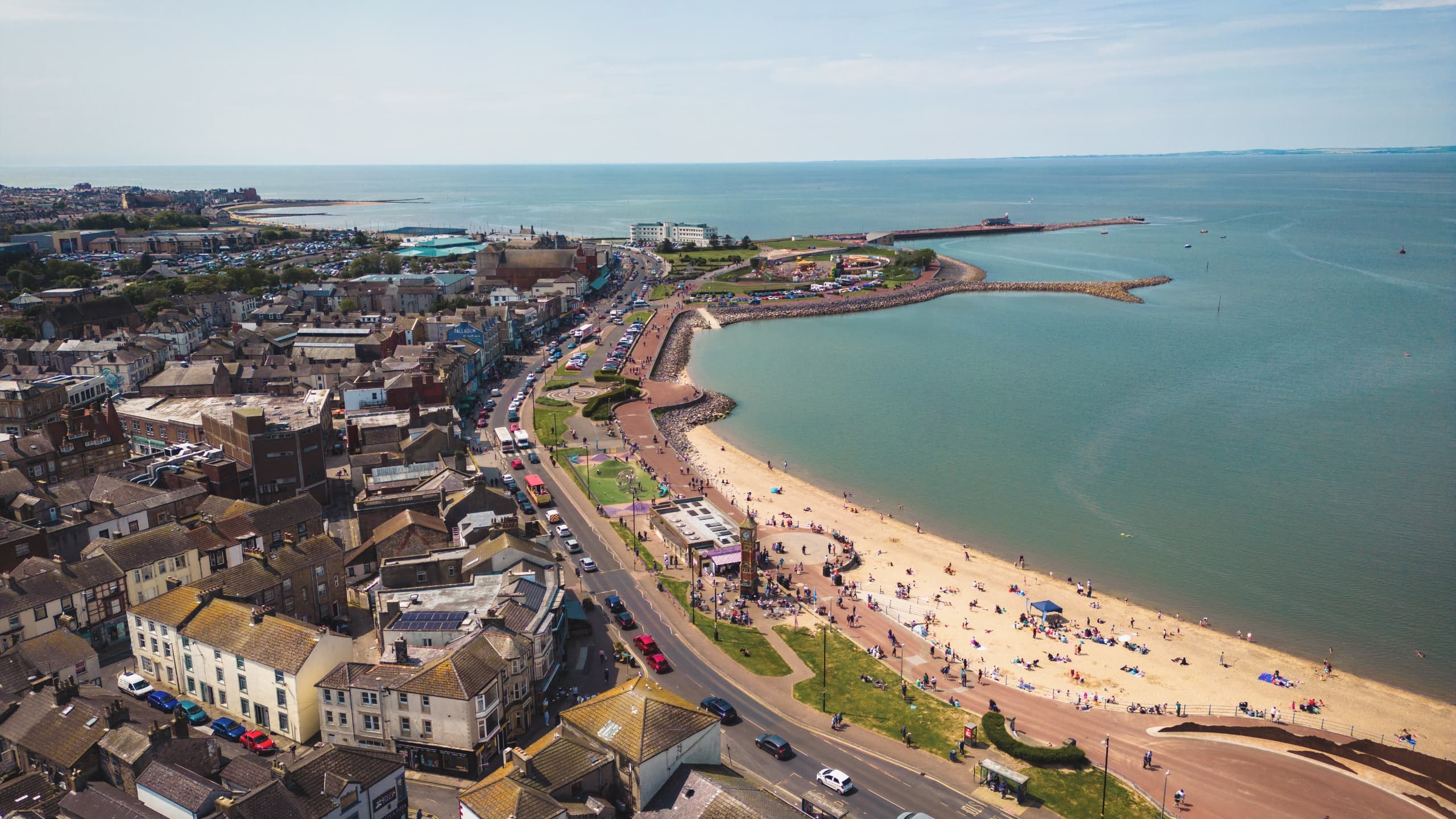 An aerial view of Morecambe, showing a sandy beach, blue seas, historic buildings and the Midland Hotel.