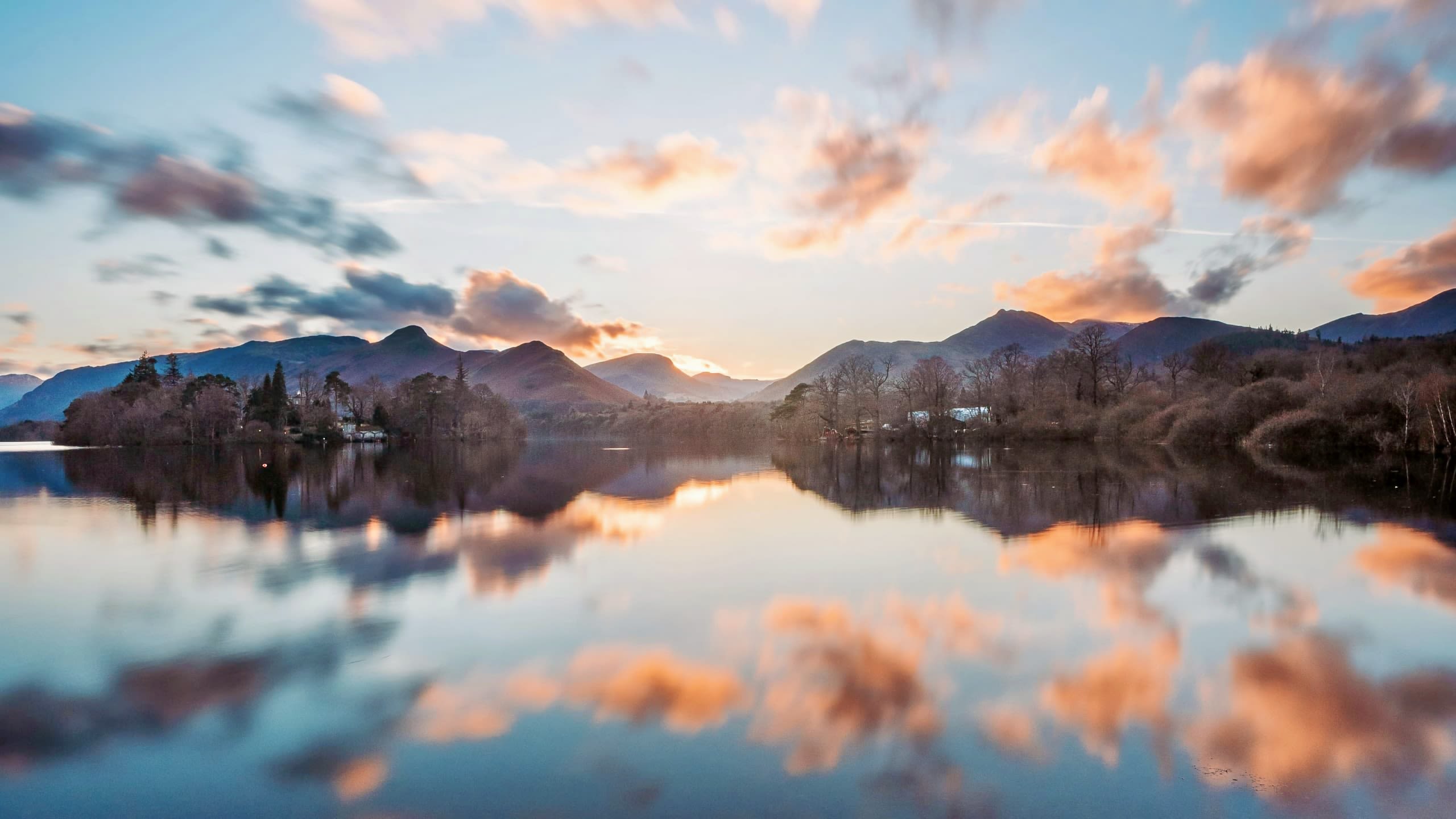 A sunset over Derwentwater with clouds and mountains perfectly reflected in the lake.