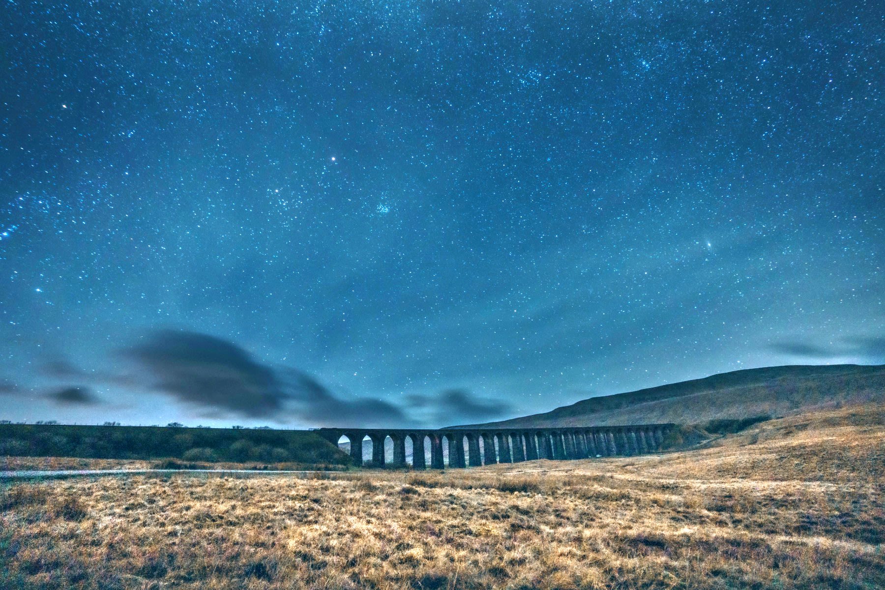 Th Ribblehead Viaduct at night, with the stars of the Milky Way visible in the sky.